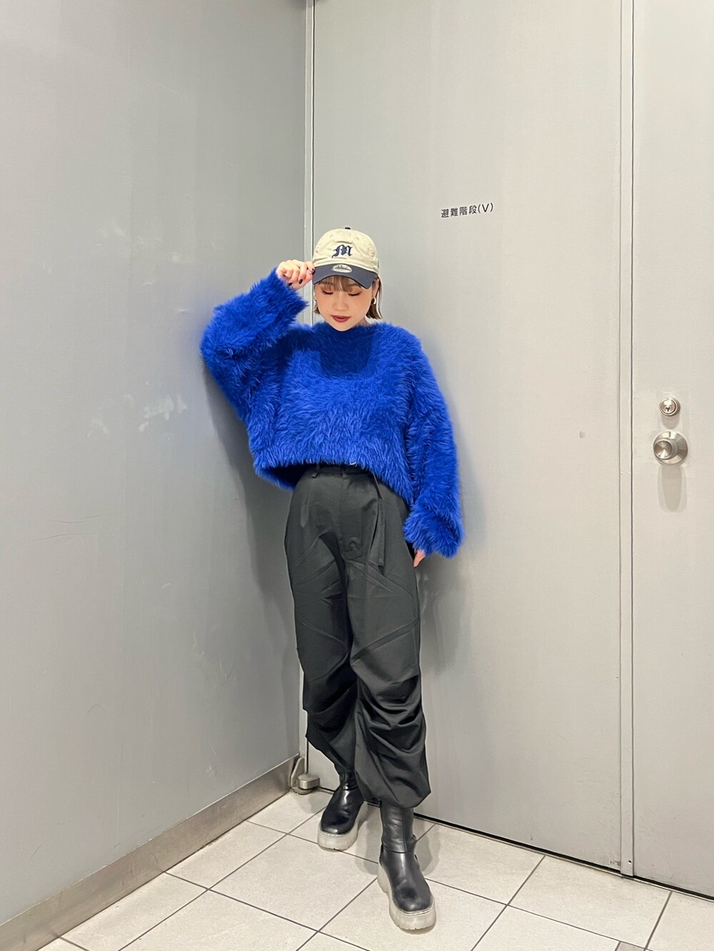 ブルー系のニット/セーター、ブラック系のその他パンツ、ブラック系のブーツを着用したレディースの秋コーディネートの2枚目の写真