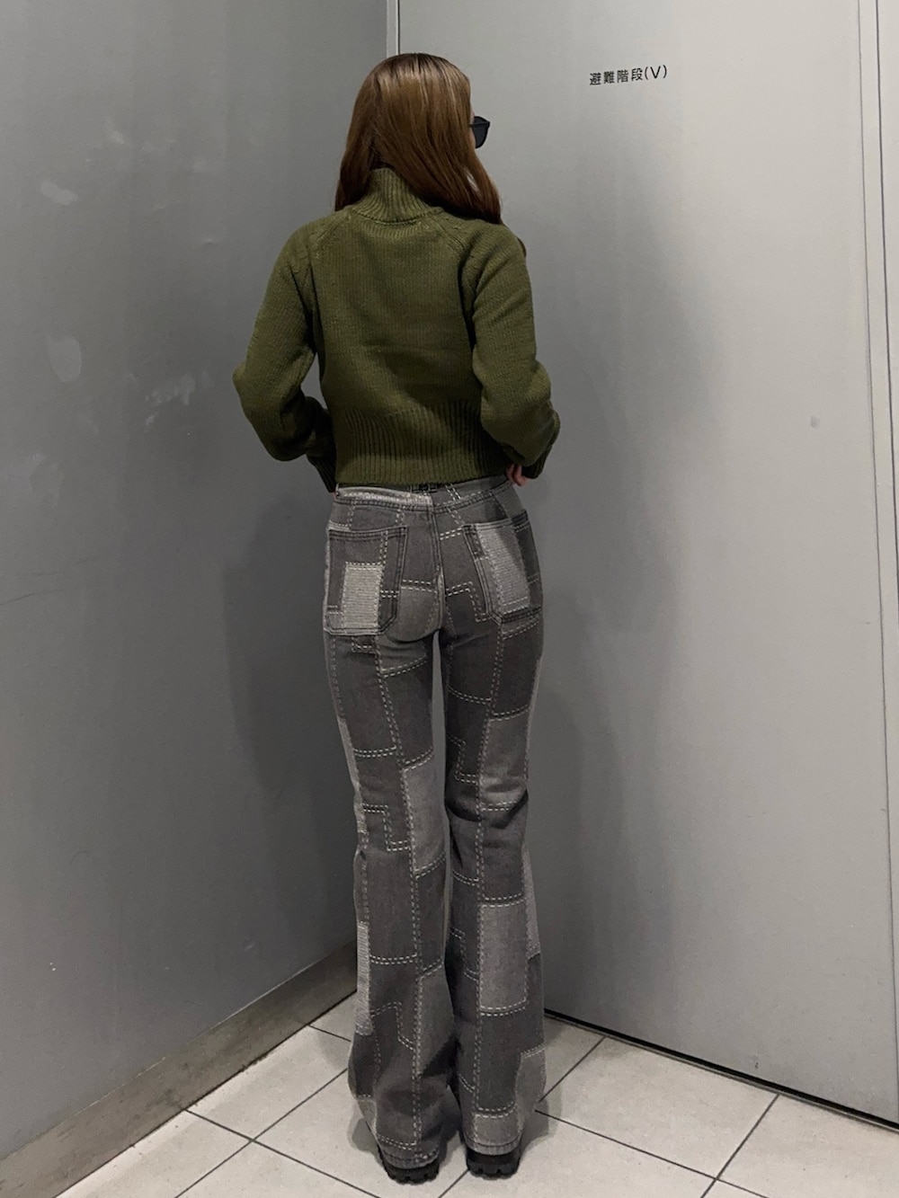 ブラック系のデニムパンツ、グリーン系のニット/セーター、ブラック系のブーツを着用したレディースの秋コーディネートの3枚目の写真