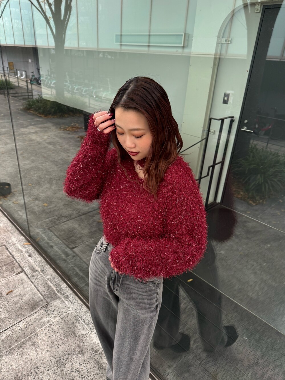 レッド系のニット/セーター、ブラック系のデニムパンツ、ブラック系のブーツを着用したレディースの冬コーディネートの4枚目の写真