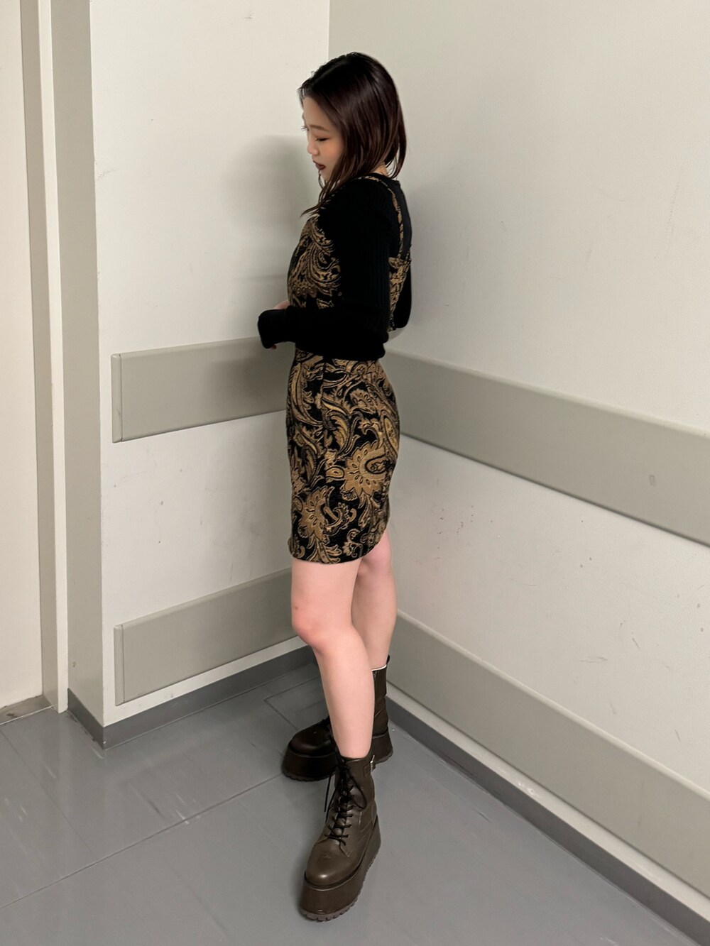 ブラック系のキャミソール、ブラック系のスカート、ブラウン系のブーツを着用したレディースの秋コーディネートの2枚目の写真