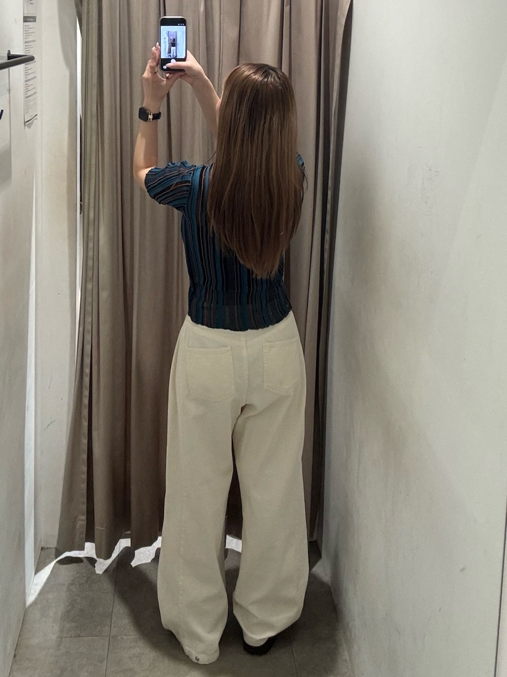 ホワイト系のデニムパンツ、ブルー系のニット/セーター、ブラック系のブーツを着用したレディースの春コーディネートの3枚目の写真