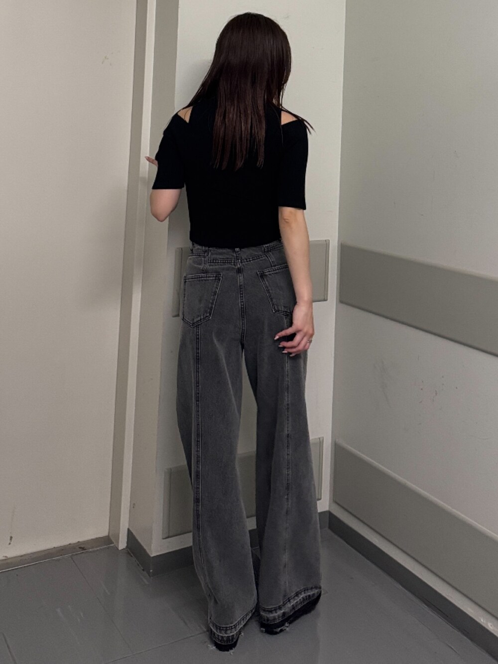 ブラック系のデニムパンツ、ブラック系のニット/セーター、ブラック系のサンダルを着用したレディースの春コーディネートの3枚目の写真