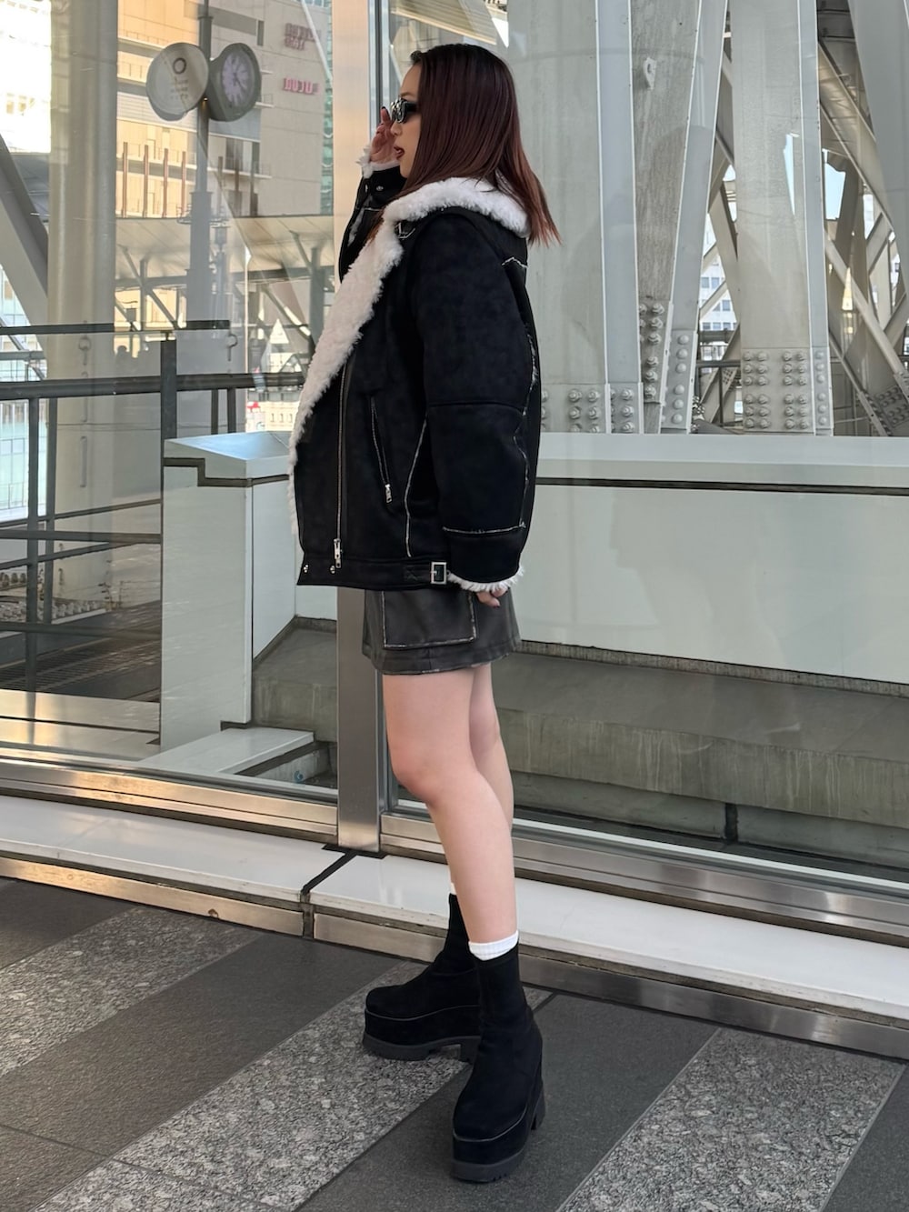 レッド系のニット/セーター、ブラウン系のスカート、ブラック系のムートンコートを着用したレディースの冬コーディネートの2枚目の写真