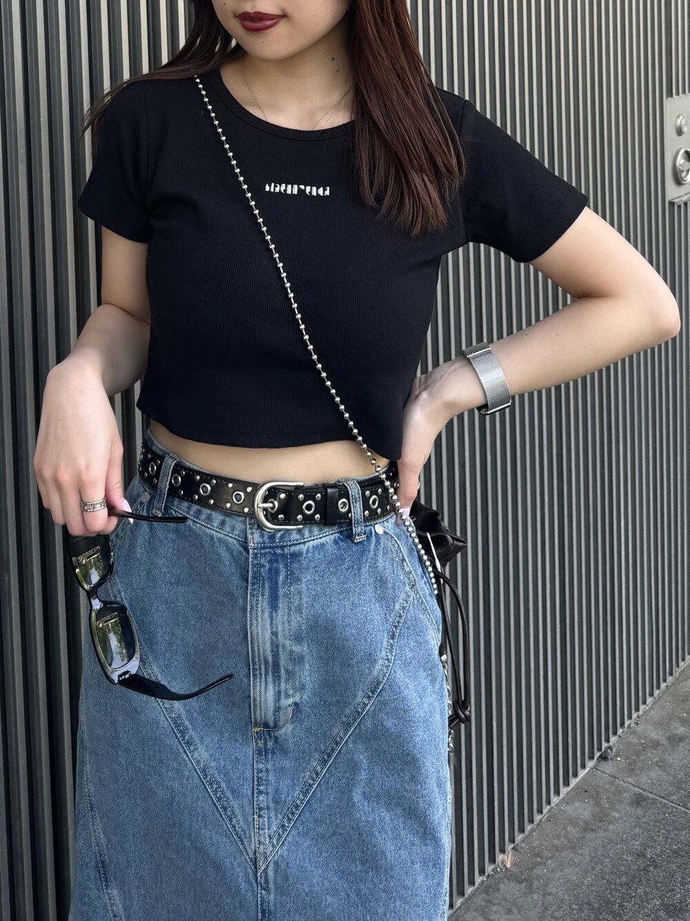 ブラック系のTシャツ/カットソー、ブルー系のデニムスカート、ブラック系のサンダルを着用したレディースの春コーディネートの5枚目の写真