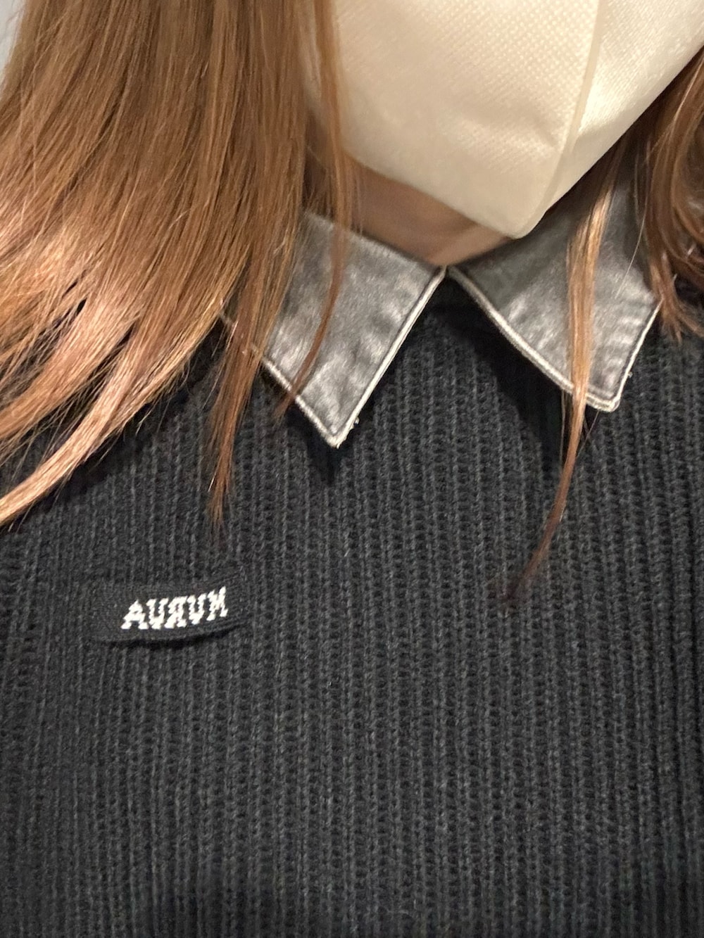 ブラック系のデニムスカート、ブラック系のニット/セーター、ブラック系のブーツを着用したレディースの冬コーディネートの6枚目の写真