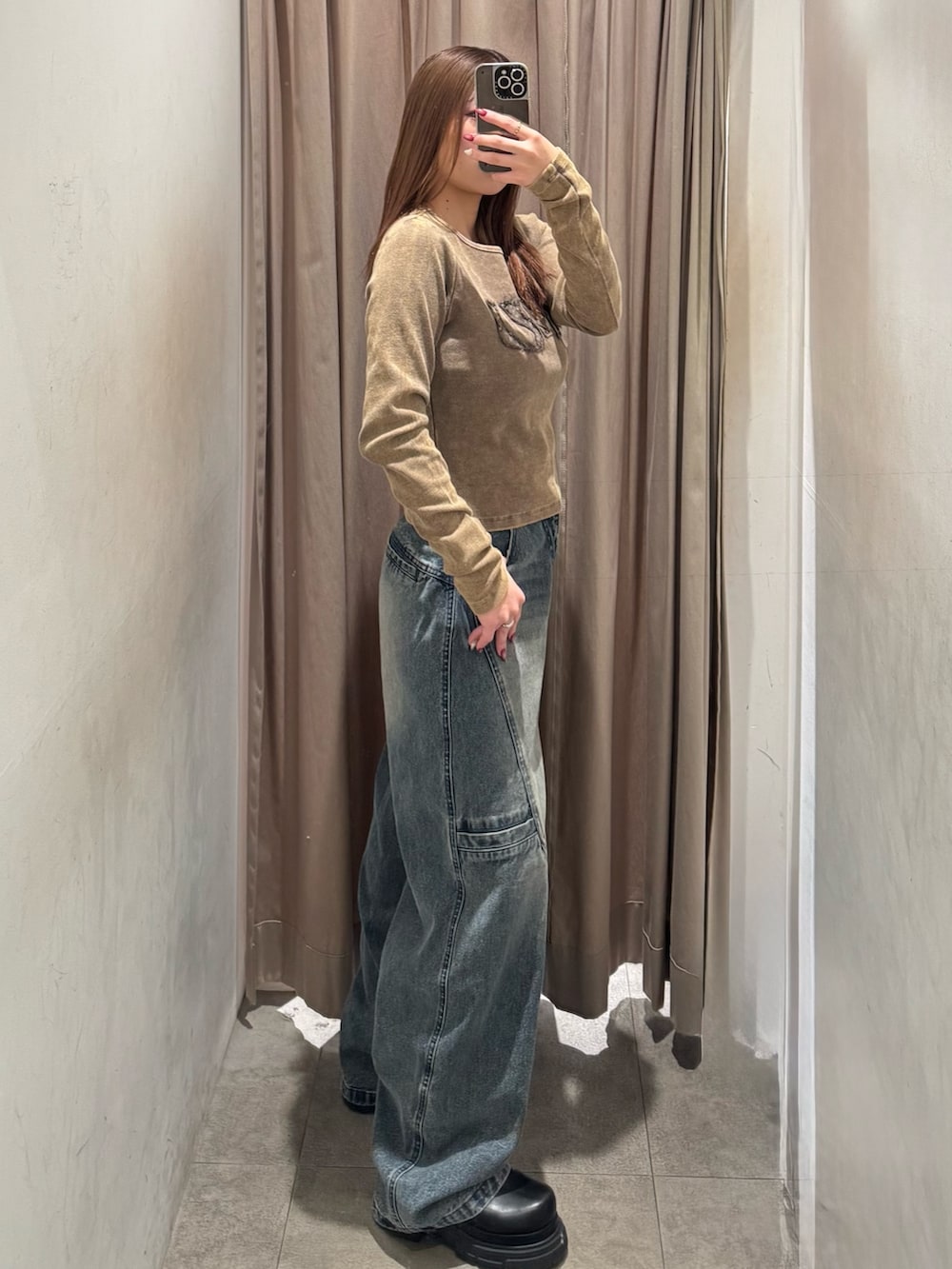 ブルー系のデニムパンツ、ブラウン系のTシャツ/カットソー、ブラック系のブーツを着用したレディースの冬コーディネートの2枚目の写真