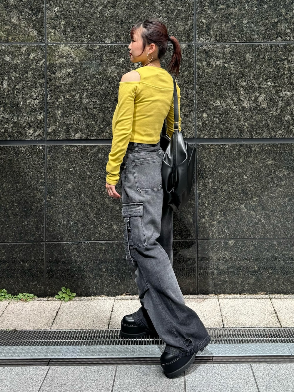 イエロー系のTシャツ/カットソー、ブラック系のデニムパンツ、ブラック系のブーツを着用したレディースの秋コーディネートの2枚目の写真