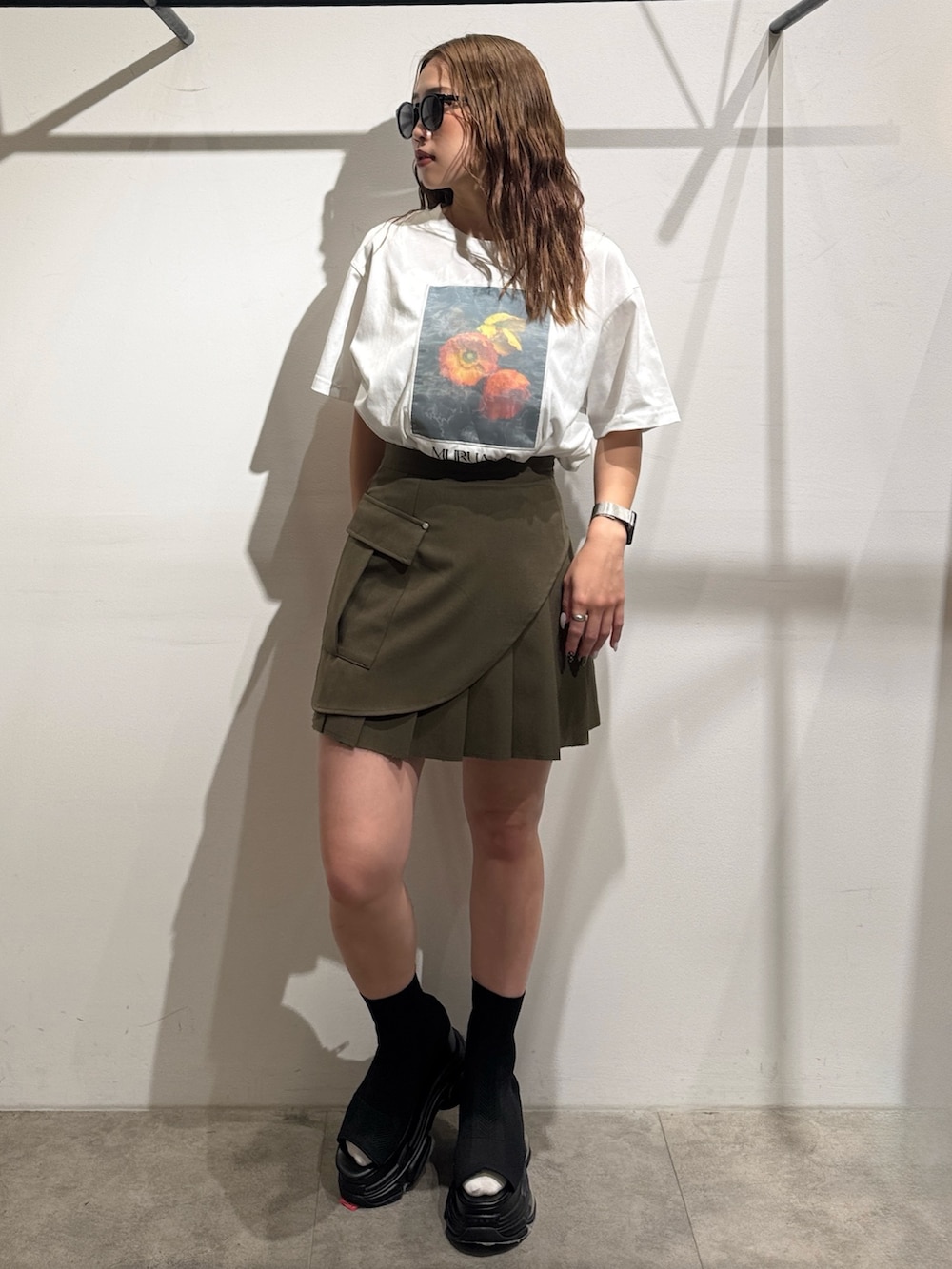 グリーン系のスカート、ホワイト系のTシャツ/カットソー、ブラック系のサンダルを着用したレディースの夏コーディネートの5枚目の写真