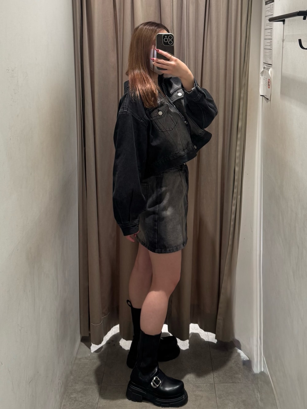 ブラック系のデニムジャケット、ブラック系のデニムスカート、ブラック系のブーツを着用したレディースの冬コーディネートの2枚目の写真