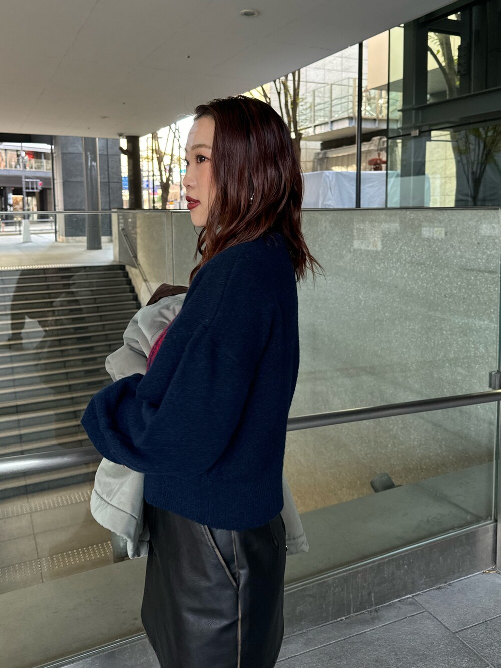 ブルー系のニット/セーター、ブラック系のスカート、ブラック系のブーツを着用したレディースの秋コーディネートの5枚目の写真