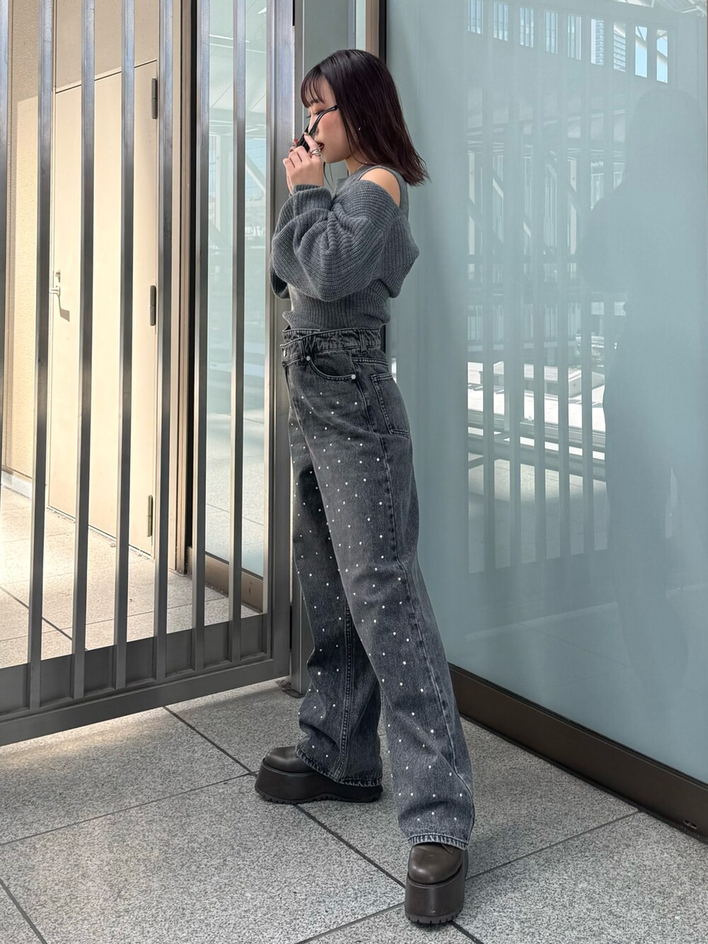 グレー系のニット/セーター、ブラック系のデニムパンツ、ブラウン系のブーツを着用したレディースの秋コーディネートの2枚目の写真