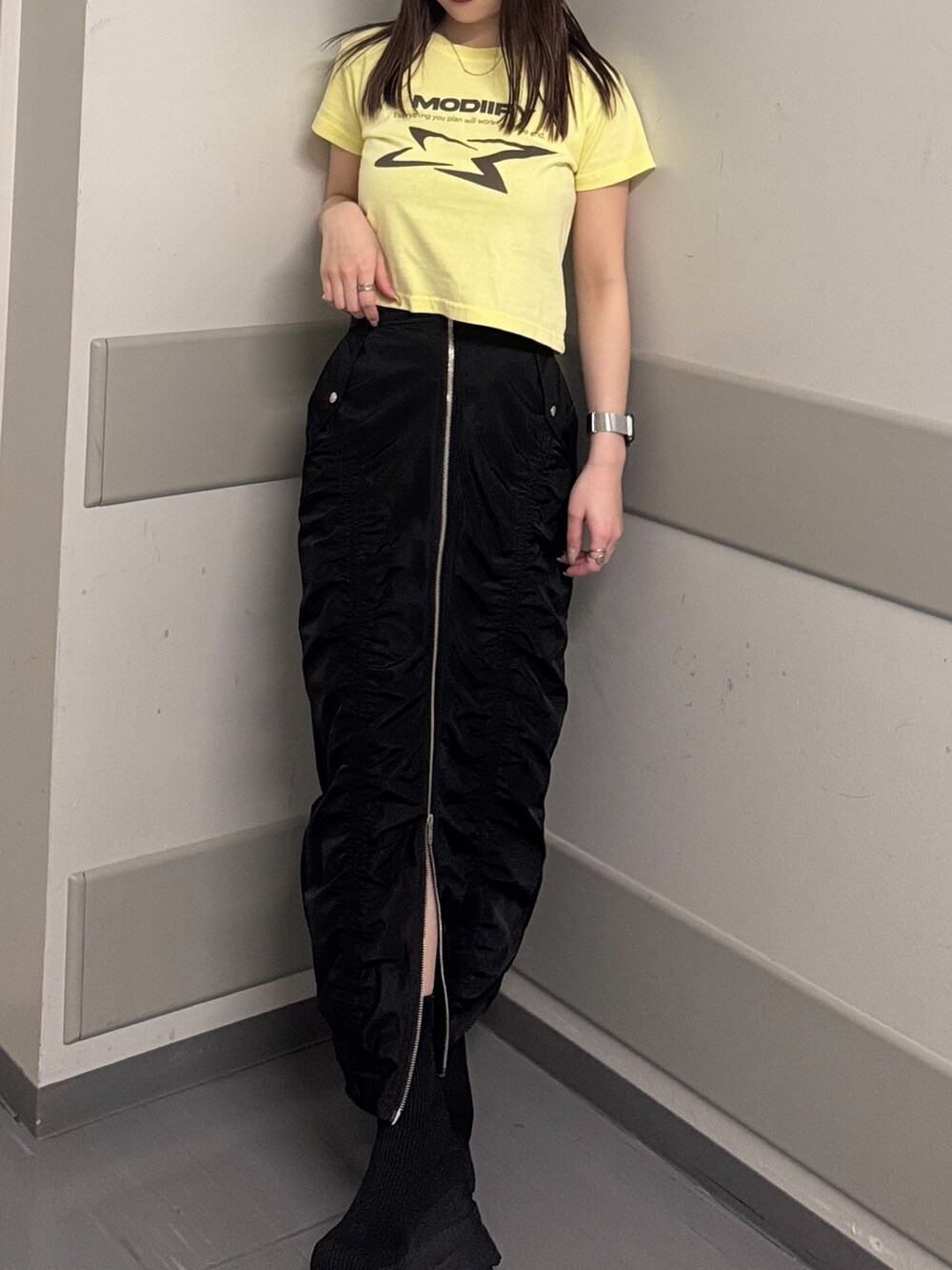 イエロー系のTシャツ/カットソー、ブラック系のスカート、ブラック系のブーツを着用したレディースの春コーディネートの6枚目の写真