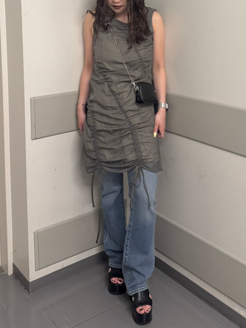 グレー系のワンピース、ブルー系のデニムパンツ、ブラック系のサンダルを着用したレディースの夏コーディネートの4枚目の写真