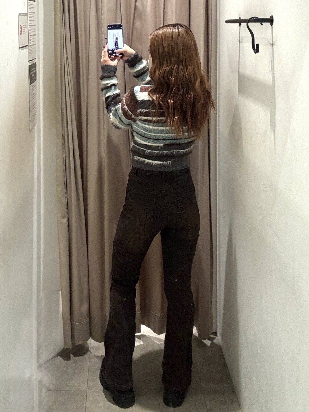 ブラウン系のデニムパンツ、ブラウン系のニット/セーター、ブラック系のブーツを着用したレディースの秋コーディネートの3枚目の写真