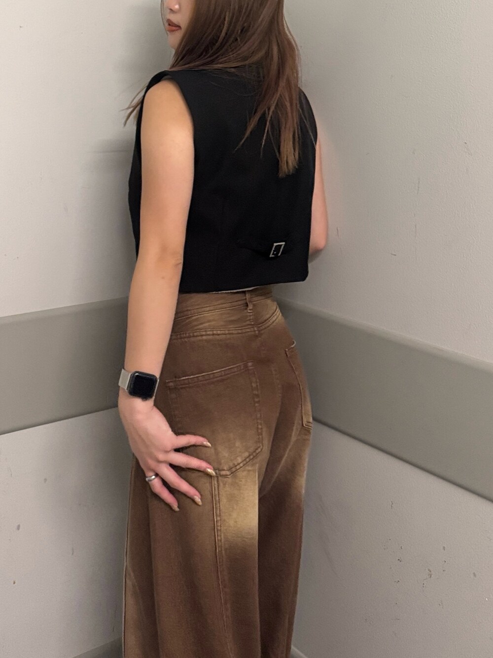 ブラウン系のデニムパンツ、グレー系のタンクトップ、ブラック系のベストを着用したレディースの夏コーディネートの5枚目の写真