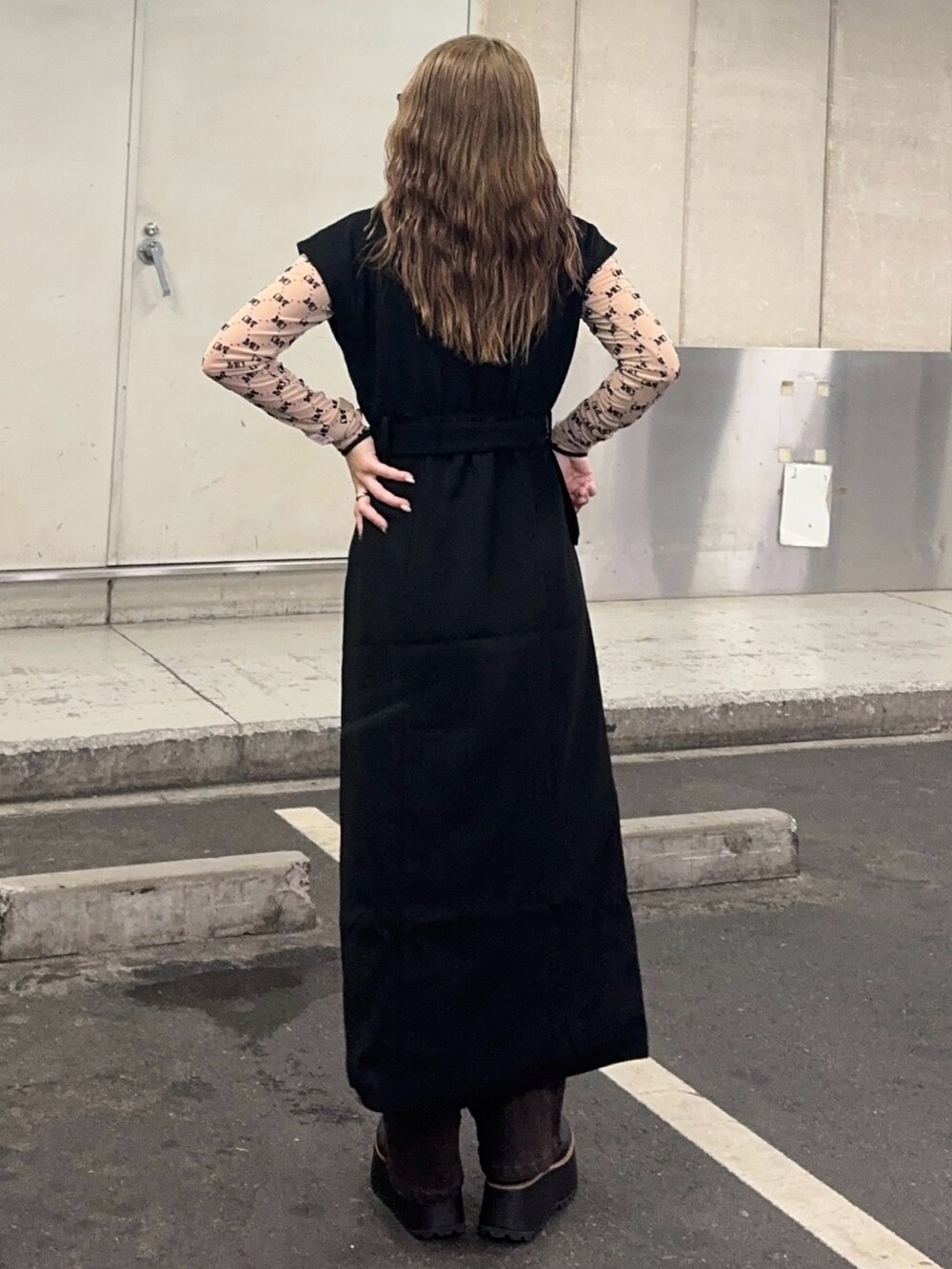 ブラウン系のデニムパンツ、ベージュ系のTシャツ/カットソー、ブラック系のワンピースを着用したレディースの秋コーディネートの3枚目の写真