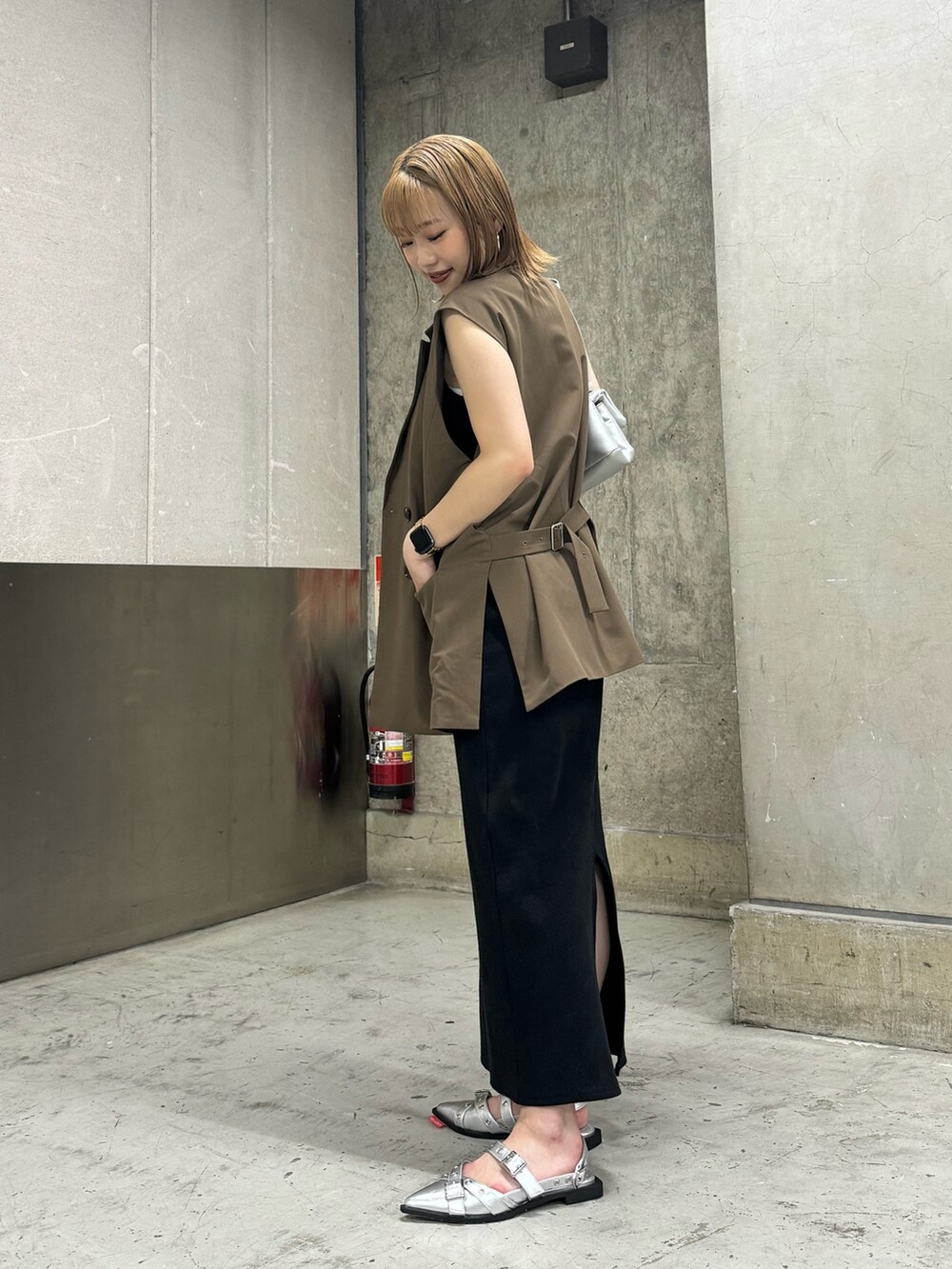 ブラウン系のベスト、ブラック系のワンピース、シルバー系のハンドバッグを着用したレディースの夏コーディネートの3枚目の写真