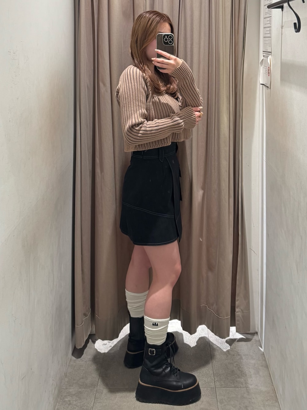ブラック系のスカート、ベージュ系のニット/セーター、ブラック系のブーツを着用したレディースの冬コーディネートの2枚目の写真