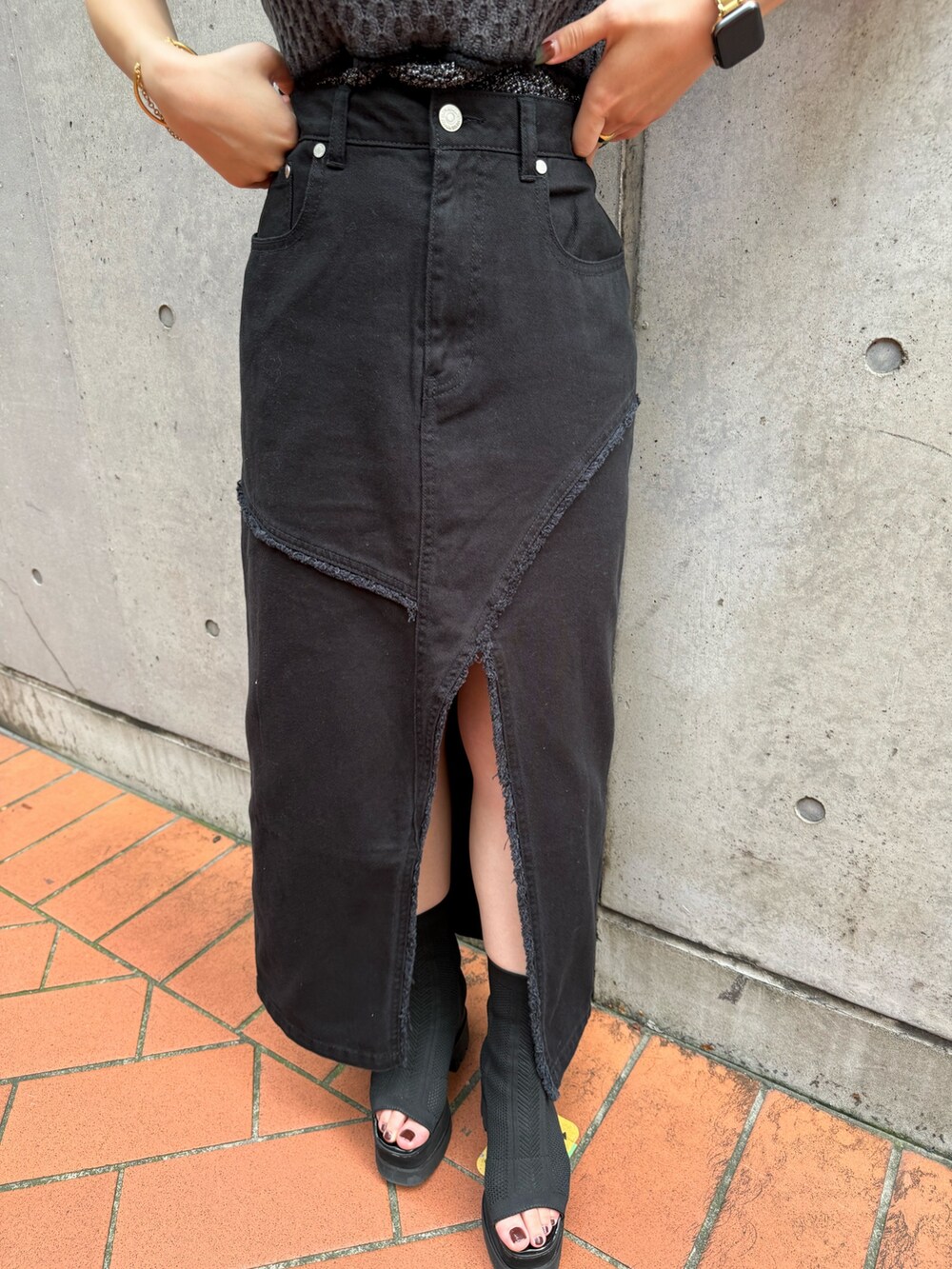 ブラック系のニット/セーター、ブラック系のデニムスカートを着用したレディースの夏コーディネートの7枚目の写真