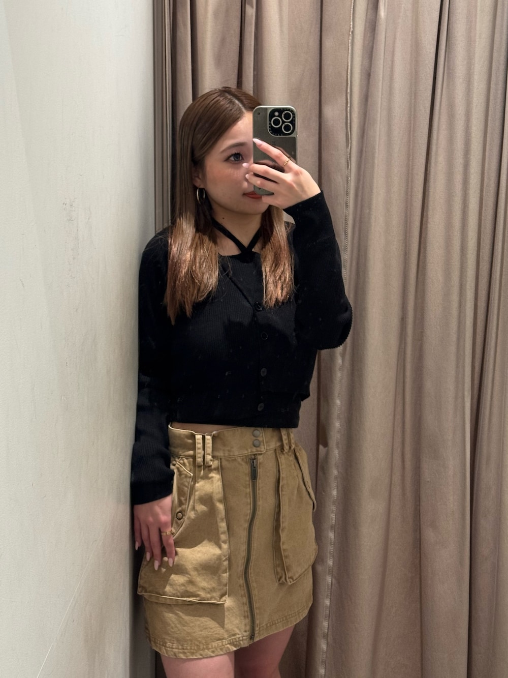 ベージュ系のスカート、ブラック系のニット/セーター、ブラック系のブーツを着用したレディースの春コーディネートの4枚目の写真