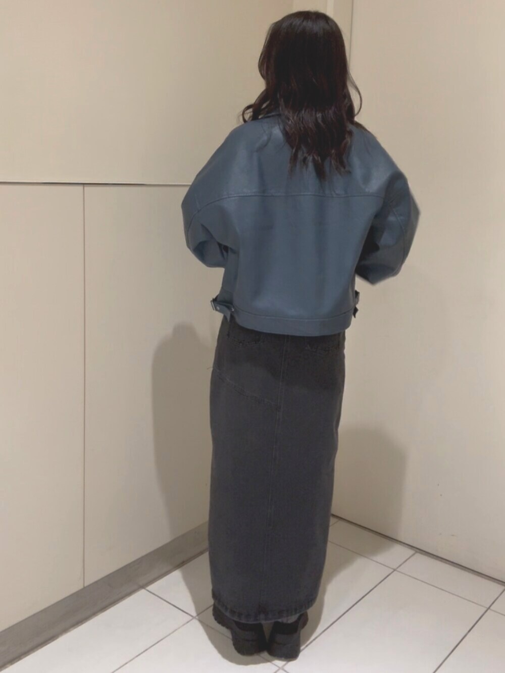 ブラック系のニット/セーター、ブルー系のブルゾン、ブラック系のデニムスカートを着用したレディースの春コーディネートの3枚目の写真