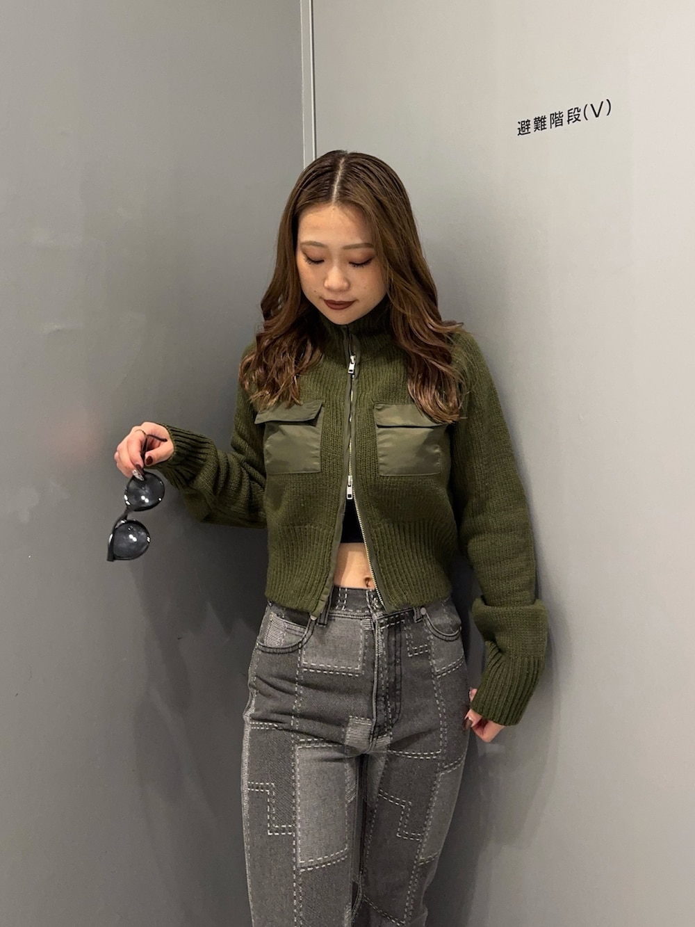 ブラック系のデニムパンツ、グリーン系のニット/セーター、ブラック系のブーツを着用したレディースの秋コーディネートの5枚目の写真