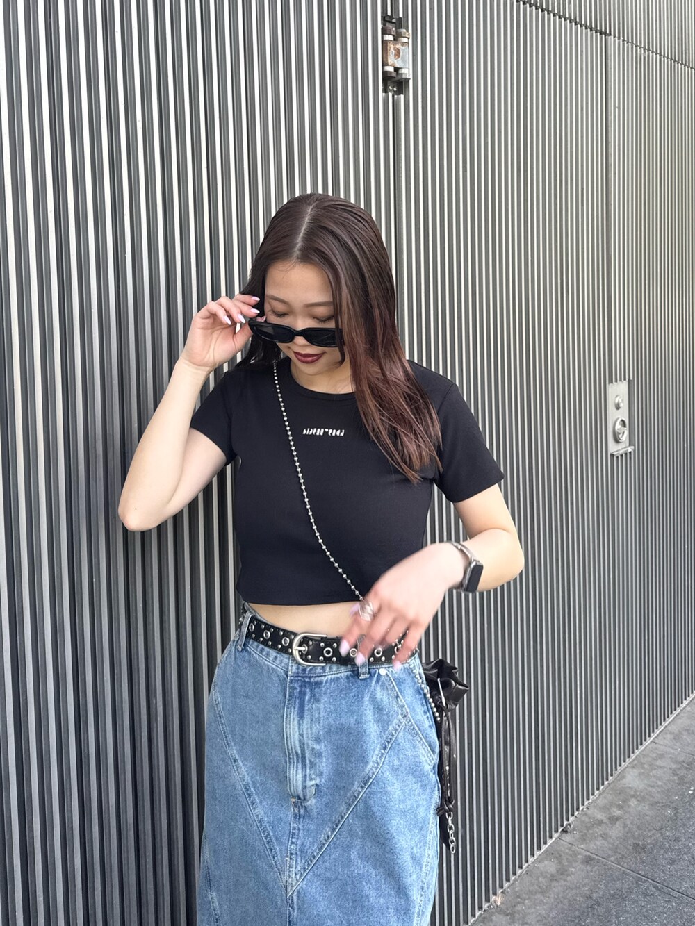ブラック系のTシャツ/カットソー、ブルー系のデニムスカート、ブラック系のサンダルを着用したレディースの春コーディネートの4枚目の写真
