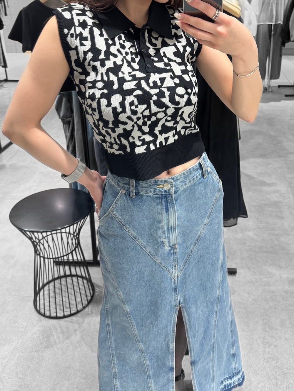 ブラック系のニット/セーター、ブルー系のデニムスカート、ブラック系のサンダルを着用したレディースの夏コーディネートの5枚目の写真