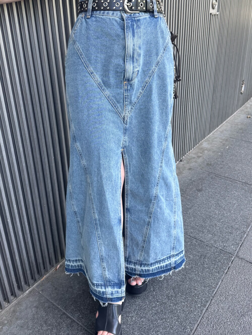 ブルー系のデニムスカート、ブラック系のタンクトップ、ブラック系のサンダルを着用したレディースの春コーディネートの6枚目の写真