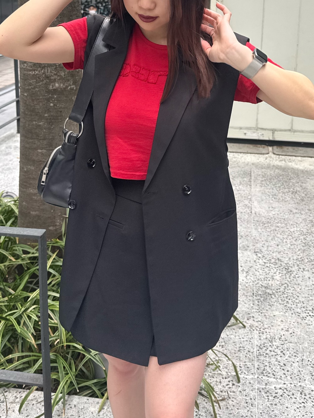 レッド系のTシャツ/カットソー、ブラック系のベスト、ブラック系のスカートを着用したレディースの春コーディネートの5枚目の写真