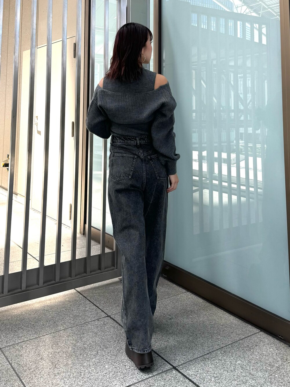 グレー系のニット/セーター、ブラック系のデニムパンツ、ブラウン系のブーツを着用したレディースの秋コーディネートの3枚目の写真