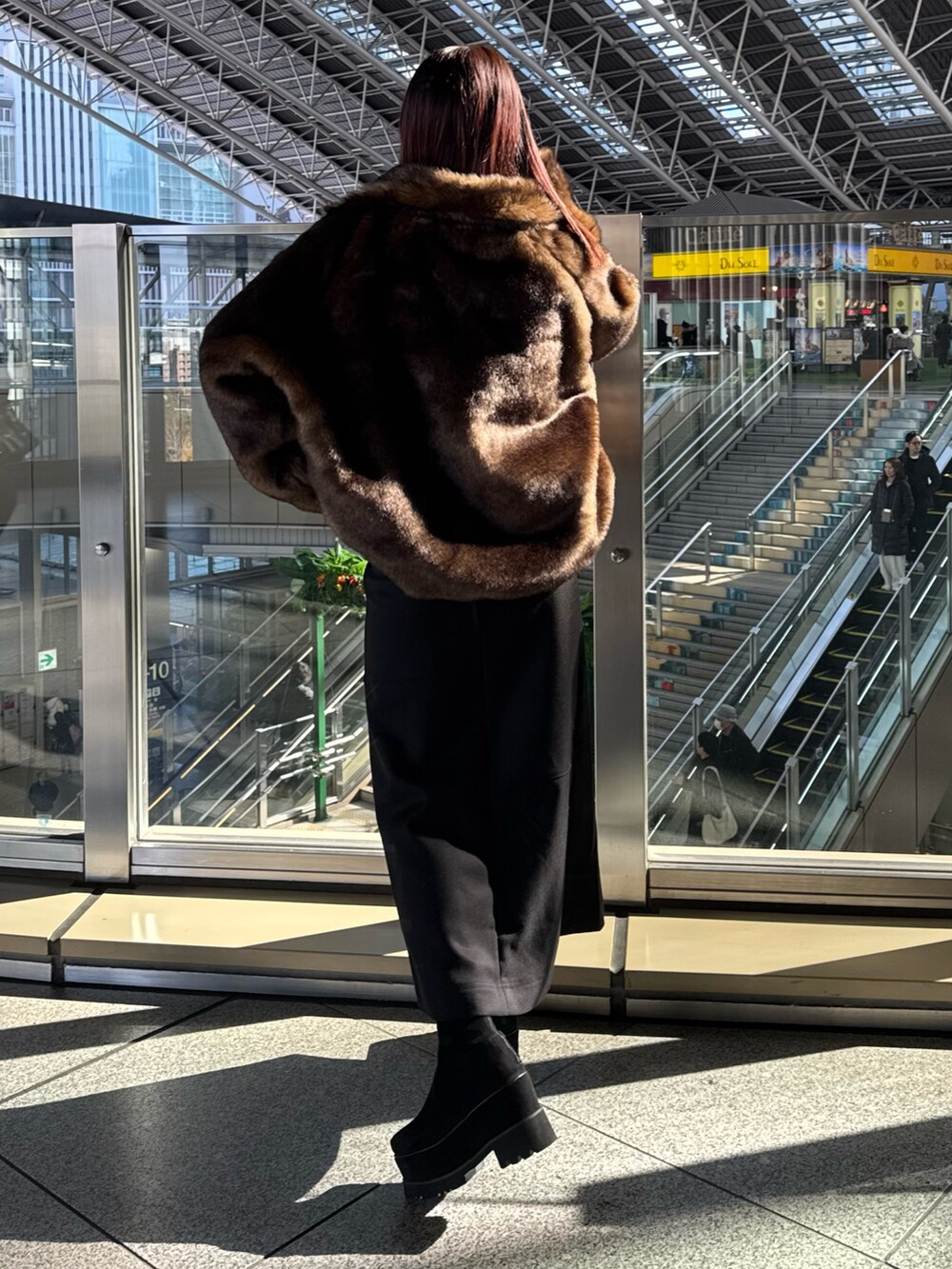 ブラウン系のブルゾン、ブラック系のスカート、ブラック系のブーツを着用したレディースの冬コーディネートの3枚目の写真