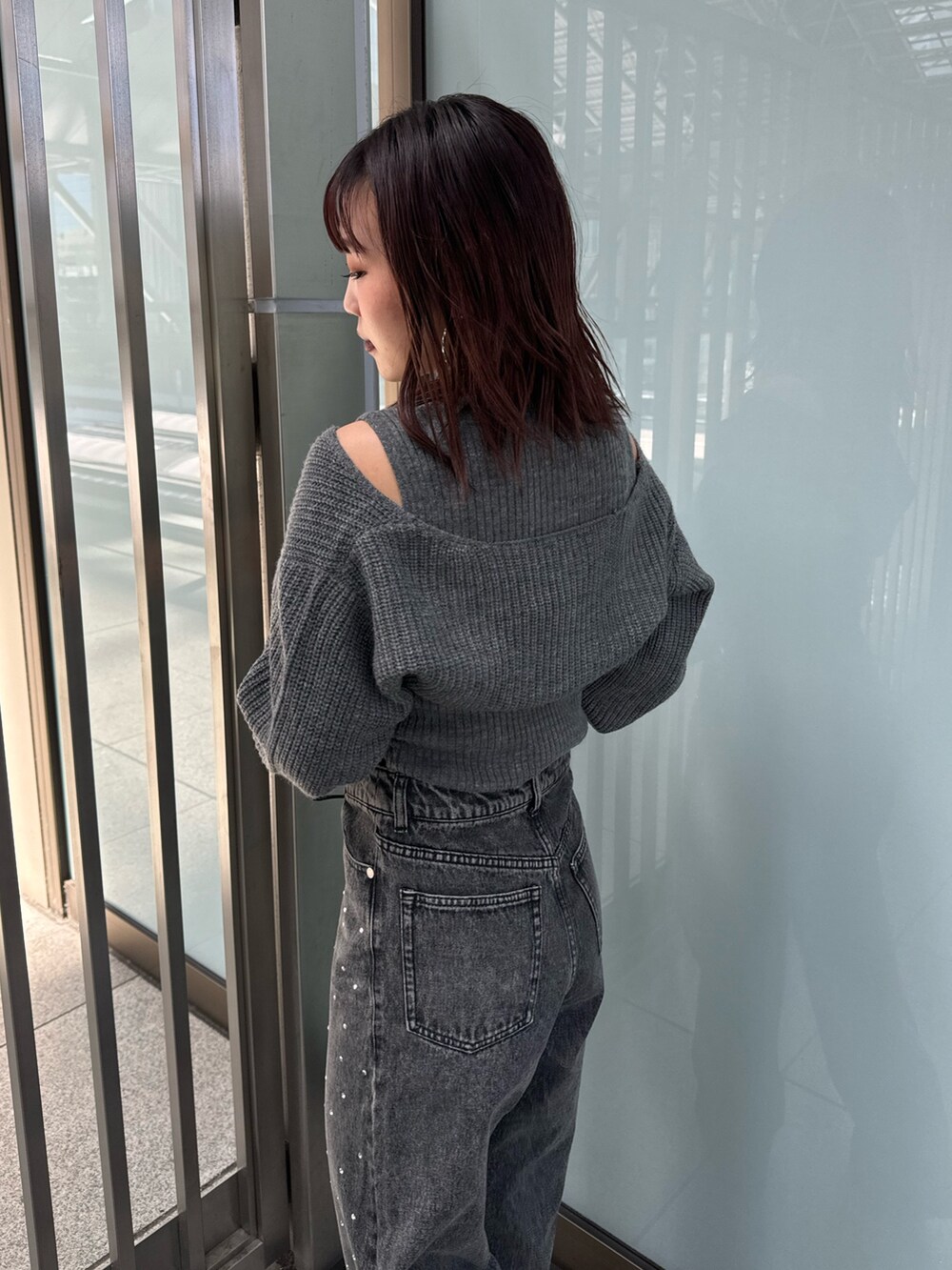 グレー系のニット/セーター、ブラック系のデニムパンツ、ブラウン系のブーツを着用したレディースの秋コーディネートの6枚目の写真