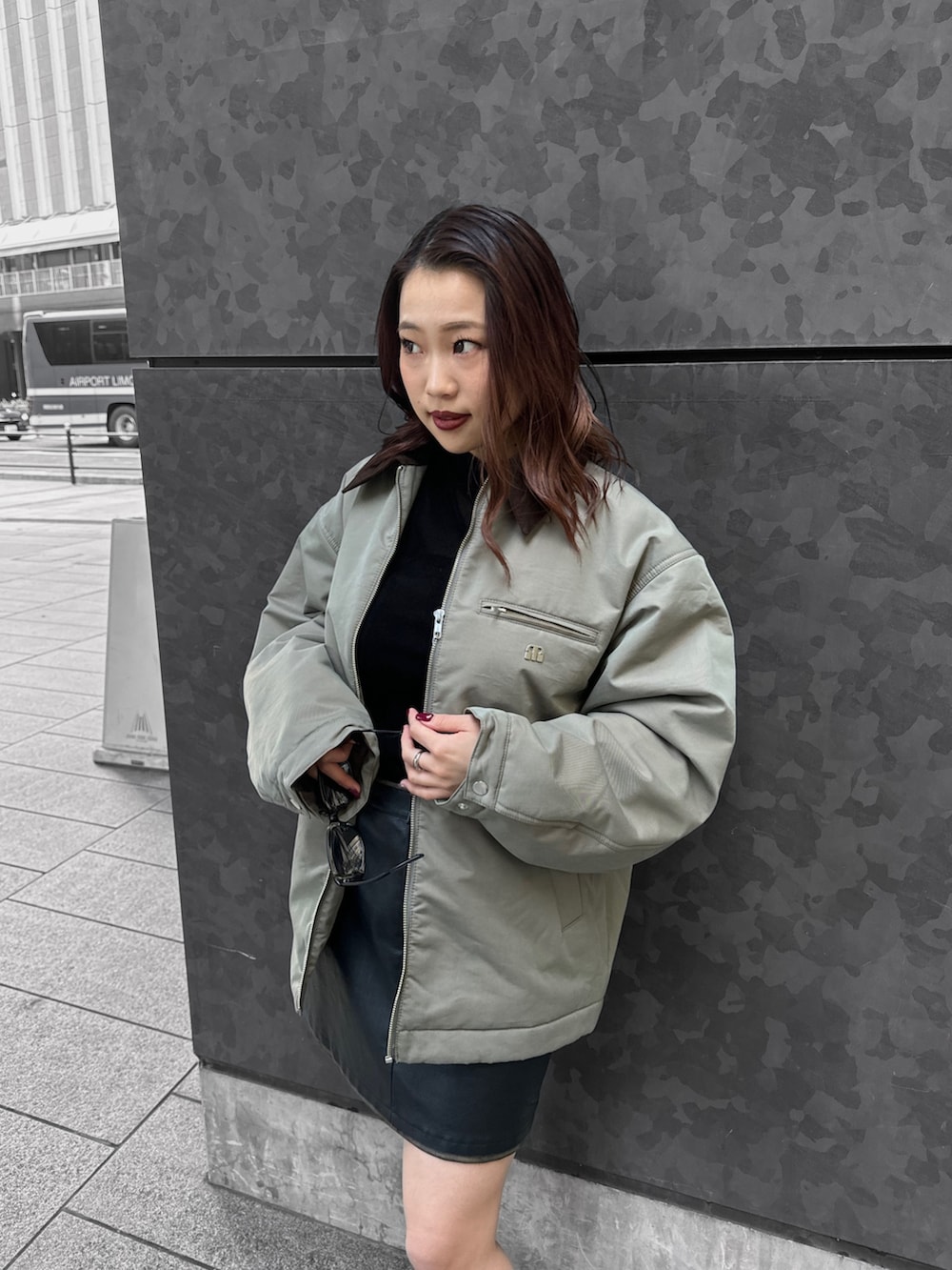 グリーン系のブルゾン、ブラック系のTシャツ/カットソー、ブラック系のスカートを着用したレディースの秋コーディネートの4枚目の写真