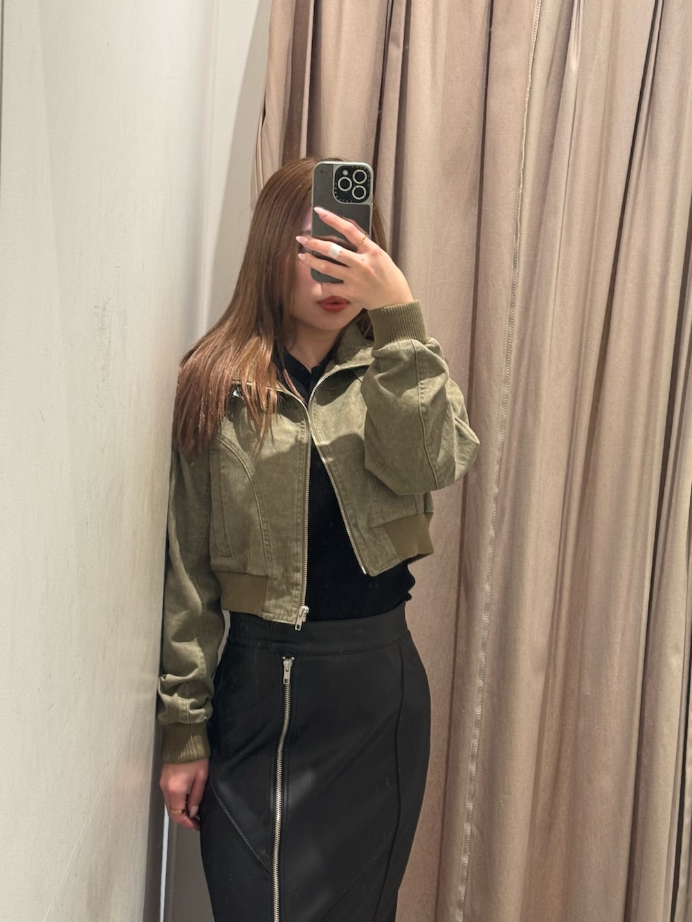 ブラック系のスカート、グリーン系のブルゾン、ブラック系のブーツを着用したレディースの春コーディネートの4枚目の写真