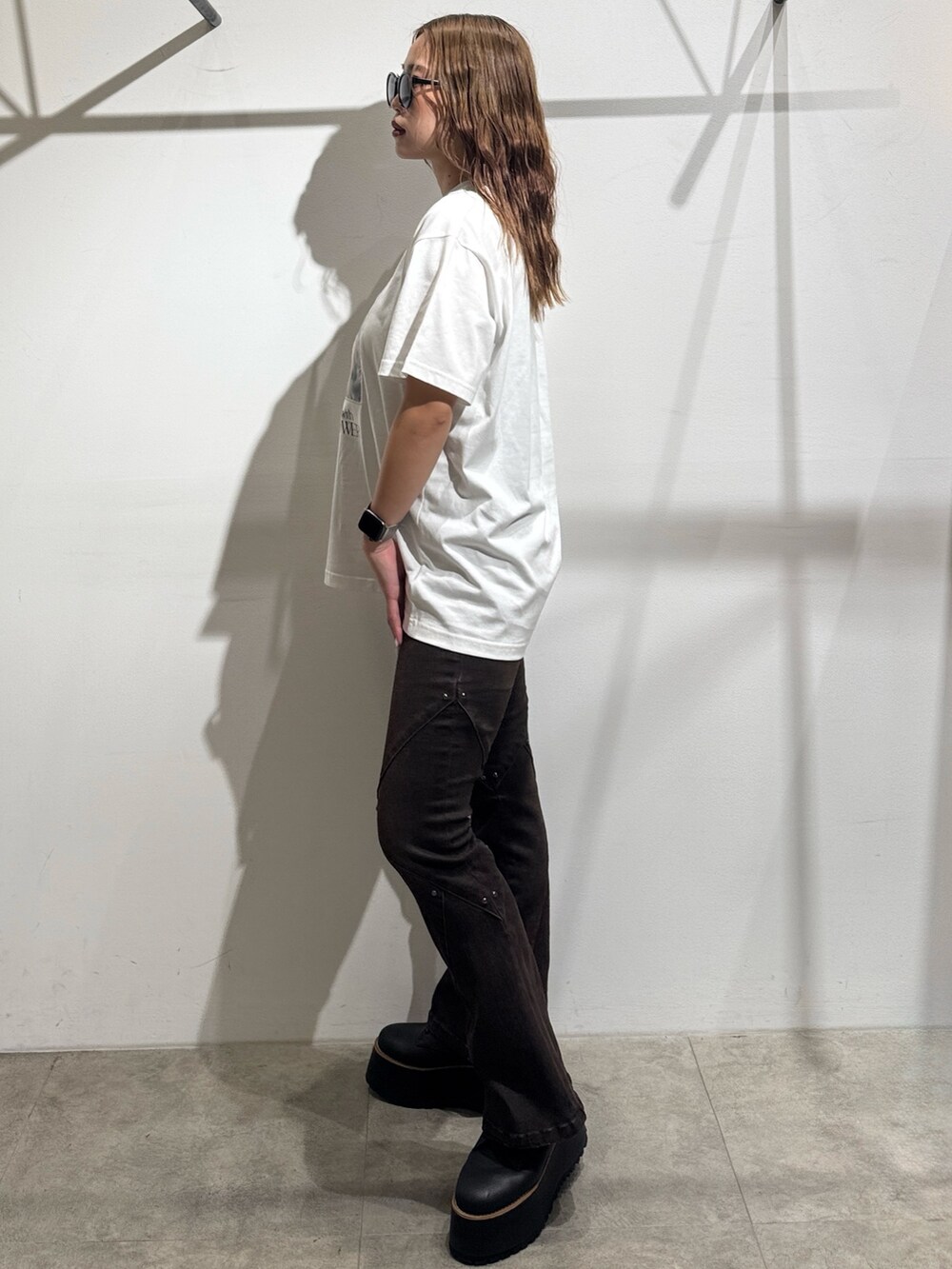 ホワイト系のTシャツ/カットソー、ブラウン系のデニムパンツ、ブラック系のブーツを着用したレディースの夏コーディネートの2枚目の写真