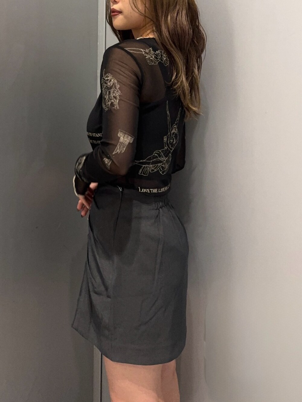 ブラック系のTシャツ/カットソー、グレー系のスカート、ブラック系のブーツを着用したレディースの秋コーディネートの5枚目の写真