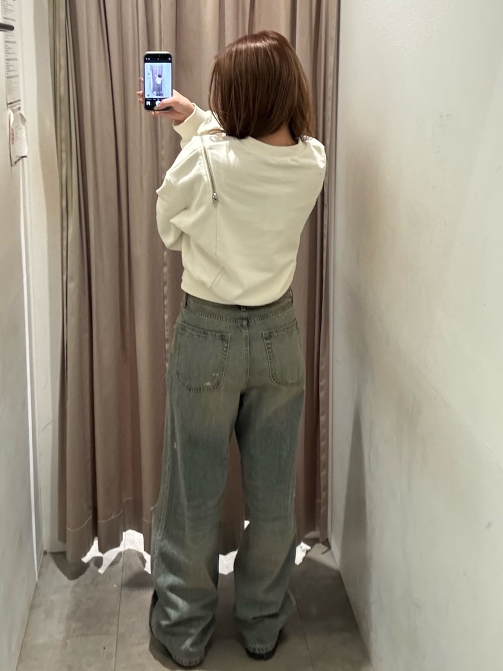 ブルー系のデニムパンツ、ホワイト系のスウェット、ブラック系のブーツを着用したレディースの冬コーディネートの3枚目の写真