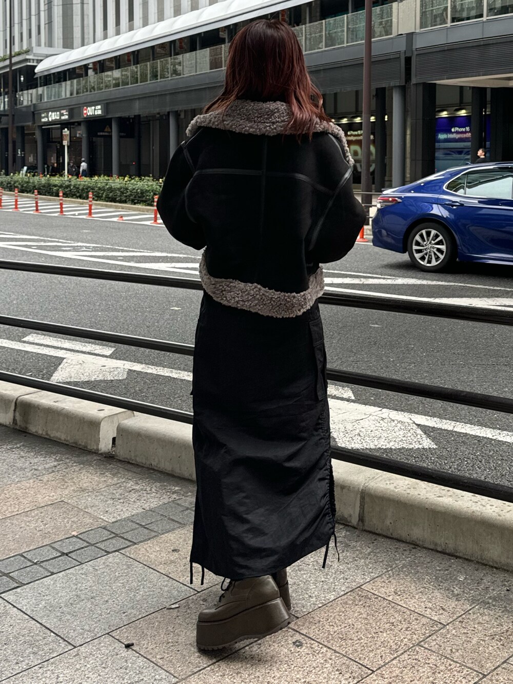 ブラック系のムートンコート、オレンジ系のニット/セーター、ブラック系のスカートを着用したレディースの冬コーディネートの3枚目の写真