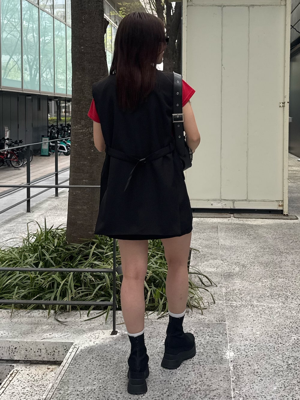 レッド系のTシャツ/カットソー、ブラック系のベスト、ブラック系のスカートを着用したレディースの春コーディネートの3枚目の写真