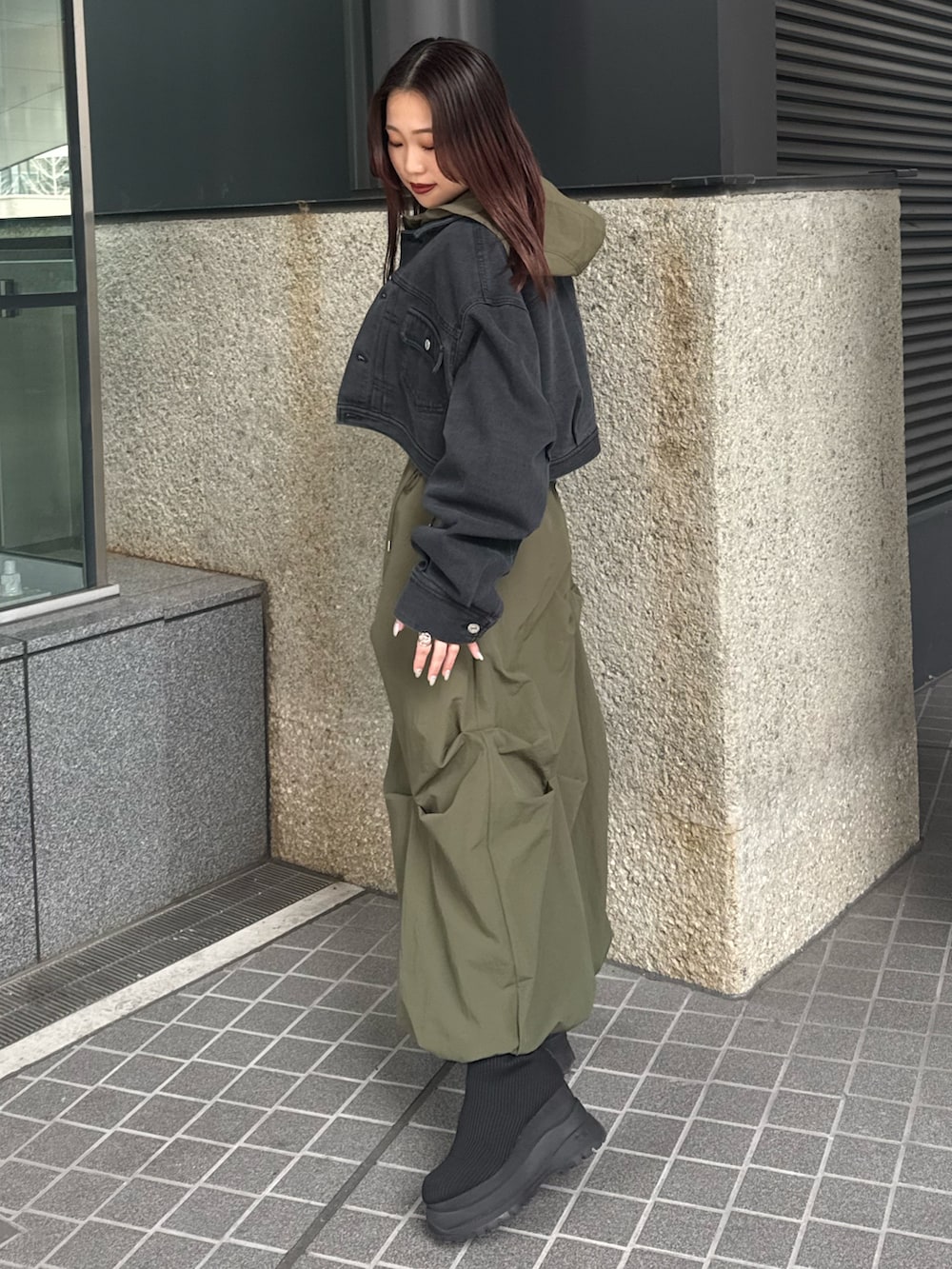 ブラック系のデニムジャケット、ベージュ系のベスト、グリーン系のスカートを着用したレディースの春コーディネートの2枚目の写真