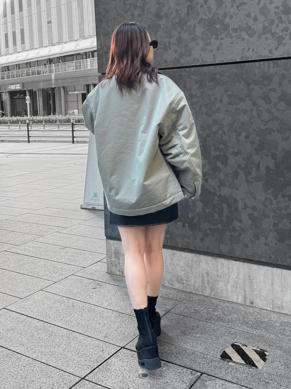 グリーン系のブルゾン、ブラック系のTシャツ/カットソー、ブラック系のスカートを着用したレディースの秋コーディネートの3枚目の写真