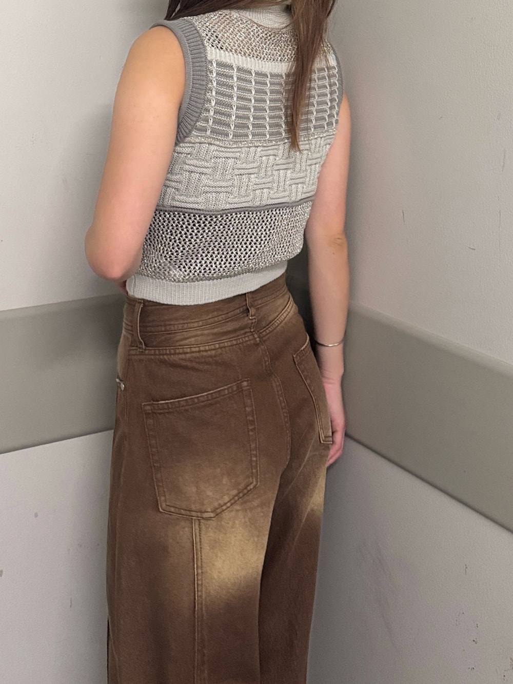 グレー系のタンクトップ、ブラウン系のデニムパンツ、ブラック系のサンダルを着用したレディースの夏コーディネートの5枚目の写真