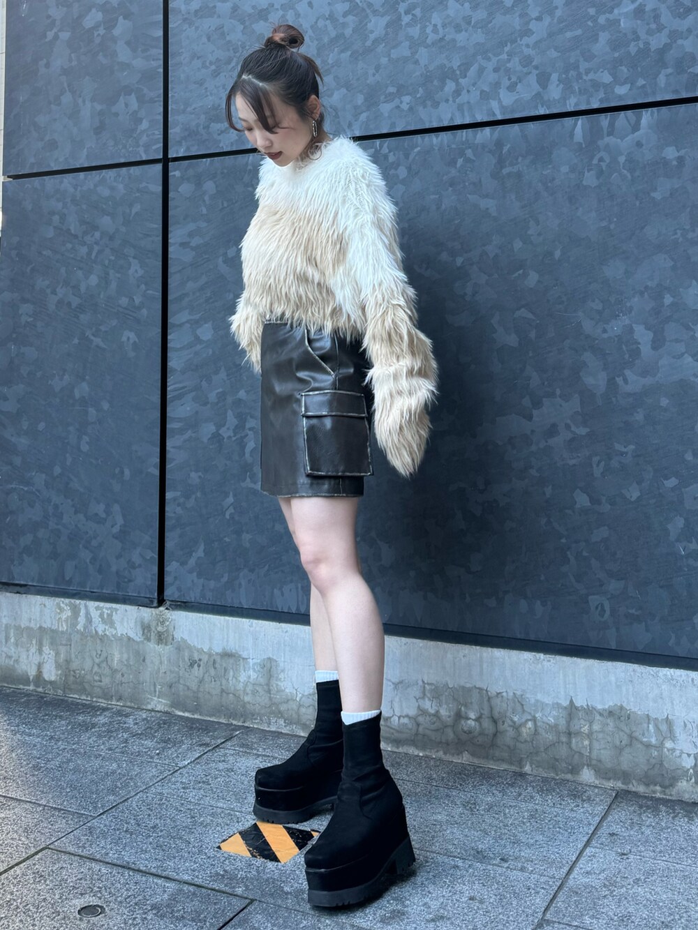 ホワイト系のニット/セーター、ブラウン系のスカート、ブラック系のブーツを着用したレディースの冬コーディネートの2枚目の写真