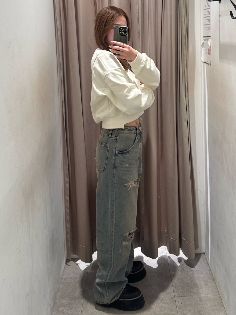 ブルー系のデニムパンツ、ホワイト系のスウェット、ブラック系のブーツを着用したレディースの冬コーディネートの2枚目の写真