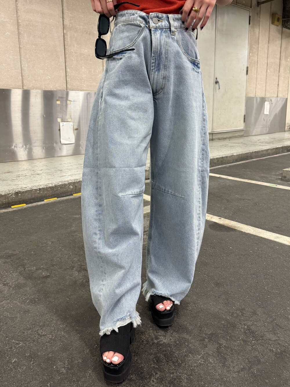 オレンジ系のニット/セーター、ブルー系のデニムパンツを着用したレディースの夏コーディネートの7枚目の写真