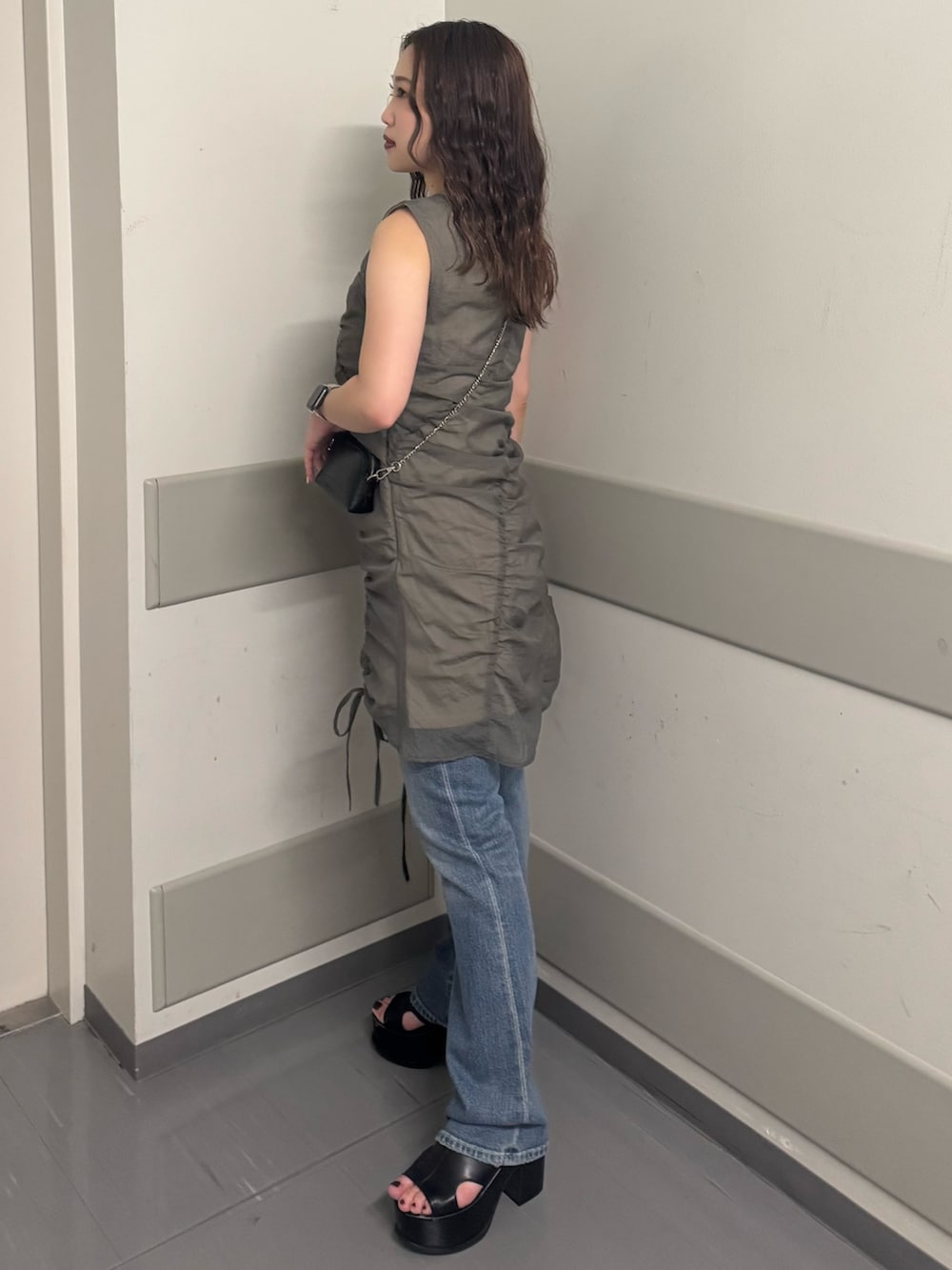 グレー系のワンピース、ブルー系のデニムパンツ、ブラック系のサンダルを着用したレディースの夏コーディネートの2枚目の写真
