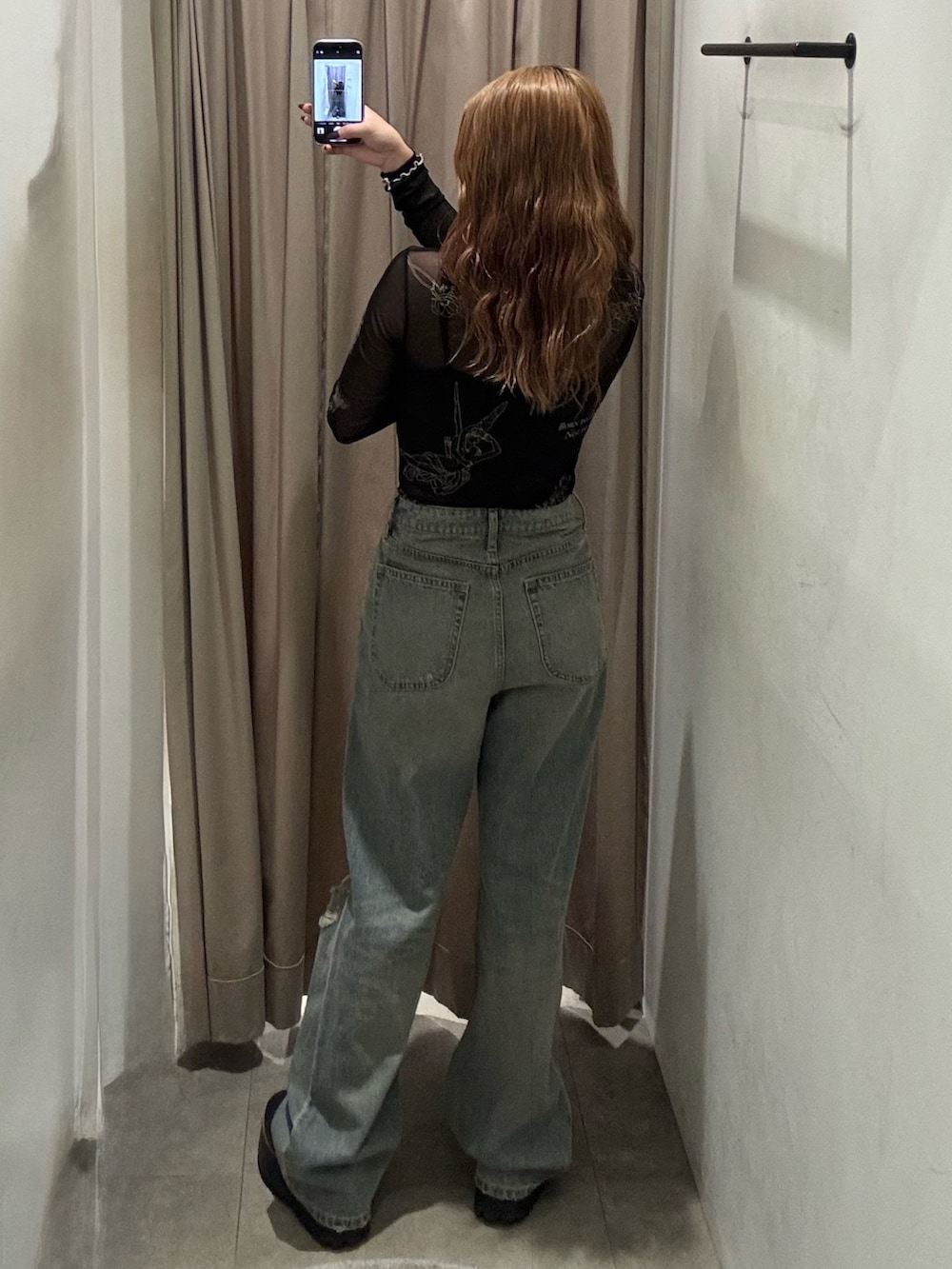 ブルー系のデニムパンツ、ブラック系のTシャツ/カットソー、ブラック系のブーツを着用したレディースの秋コーディネートの3枚目の写真