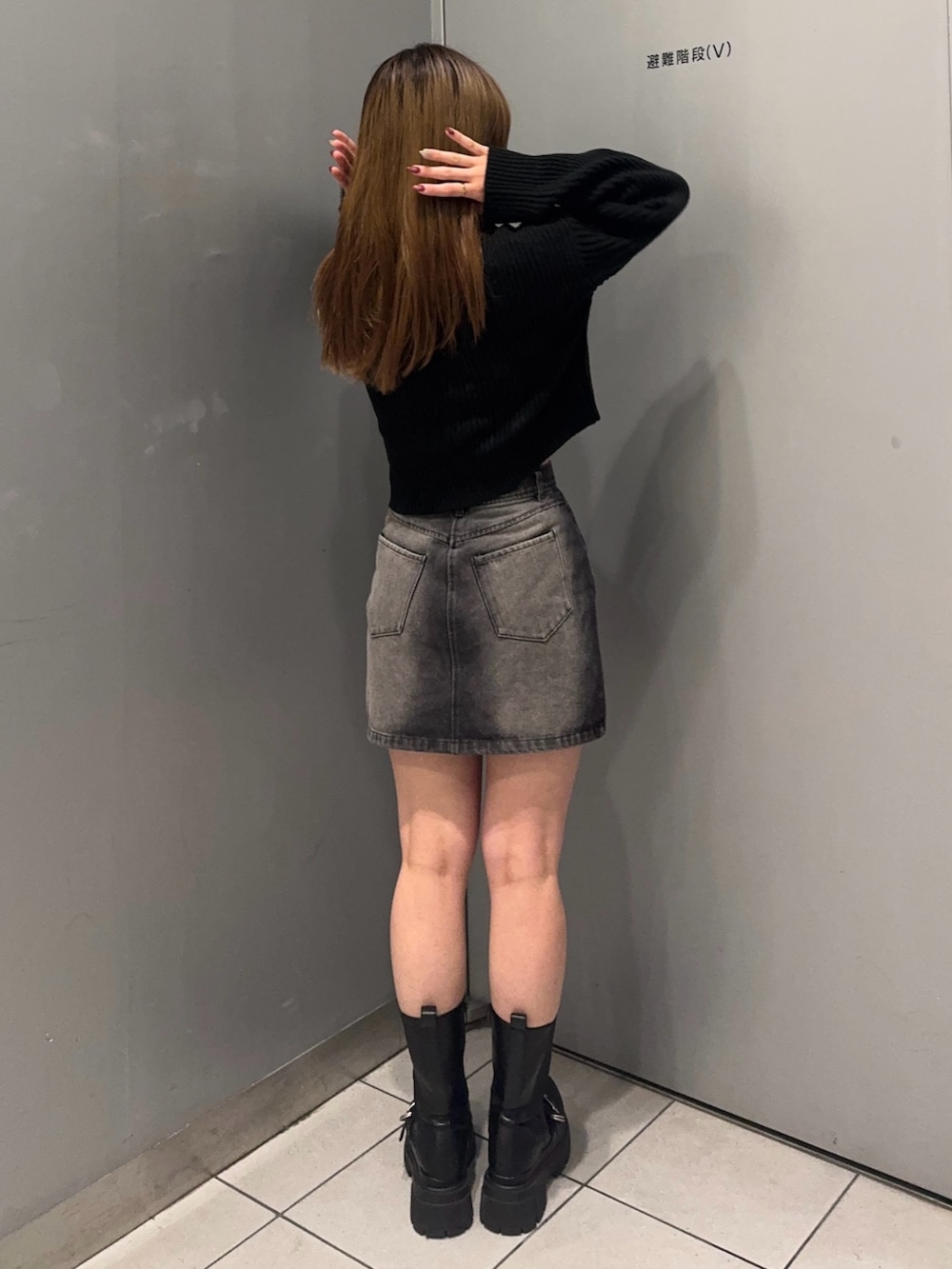 ブラック系のデニムスカート、ブラック系のニット/セーター、ブラック系のブーツを着用したレディースの冬コーディネートの3枚目の写真