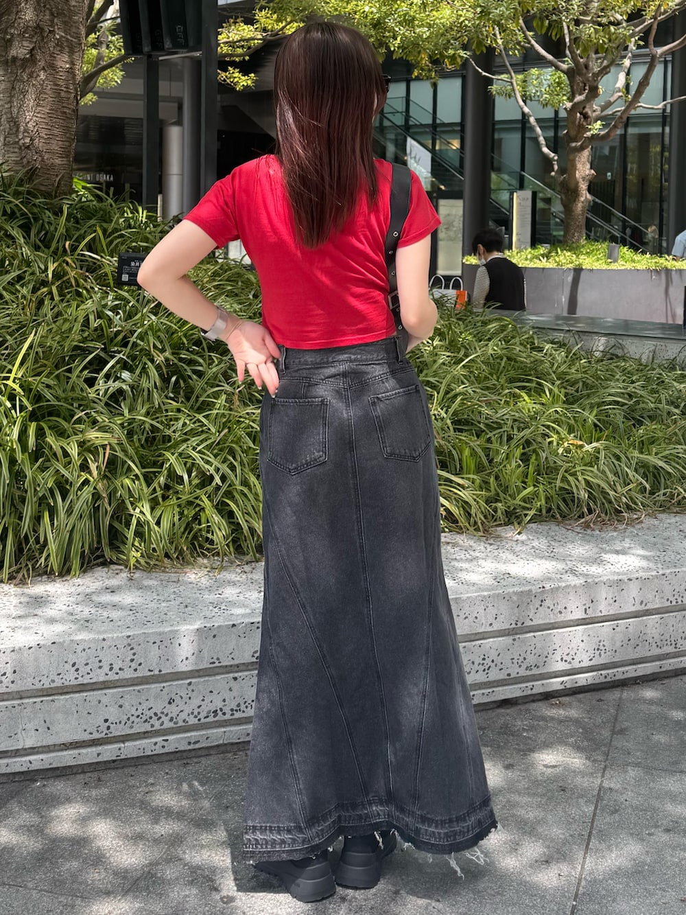 レッド系のTシャツ/カットソー、ブラック系のデニムスカート、ブラック系のブーツを着用したレディースの春コーディネートの3枚目の写真